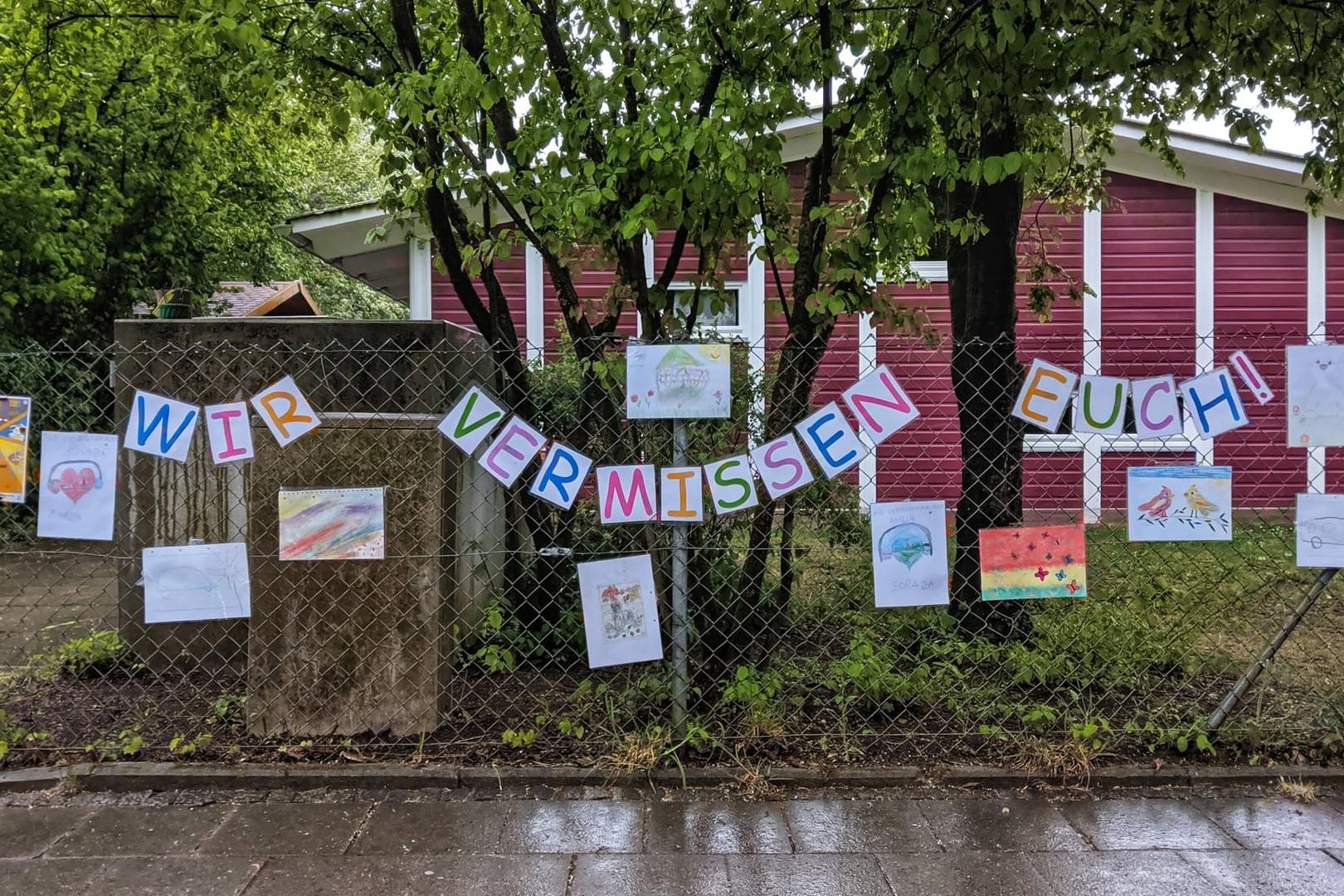 "Wir vermissen euch" steht auf Zetteln, die am Zaun einer Kita hängen: Noch dürfen nicht alle Kinder wieder in die Betreuung.