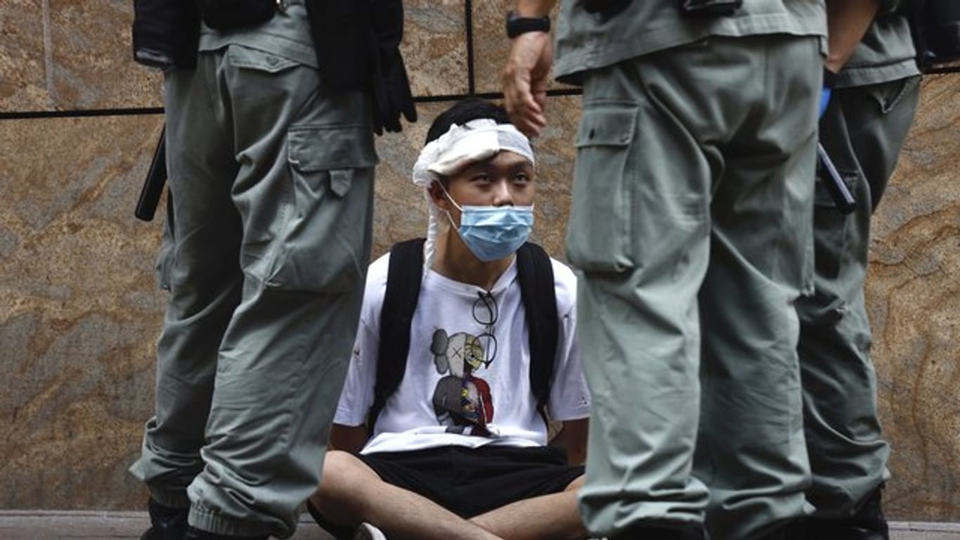Bereitschaftspolizisten stehen im Hongkonger Central District um einen auf dem Boden sitzenden Demonstranten.