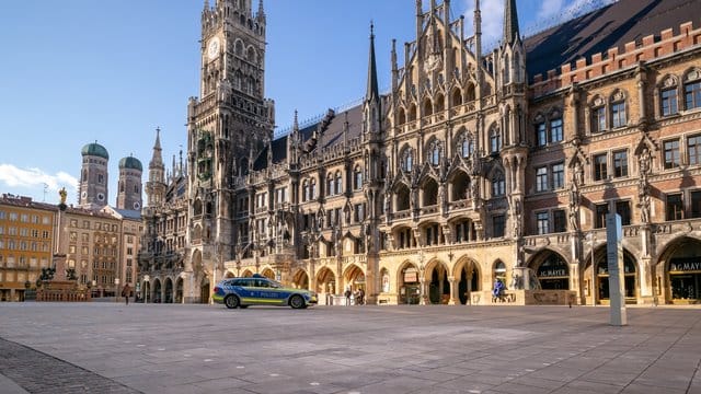 Ein Polizeiauto fährt über den fast leeren Marienplatz.