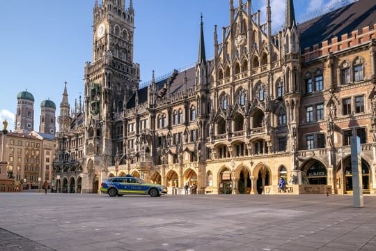 Ein Polizeiauto fährt über den fast leeren Marienplatz.