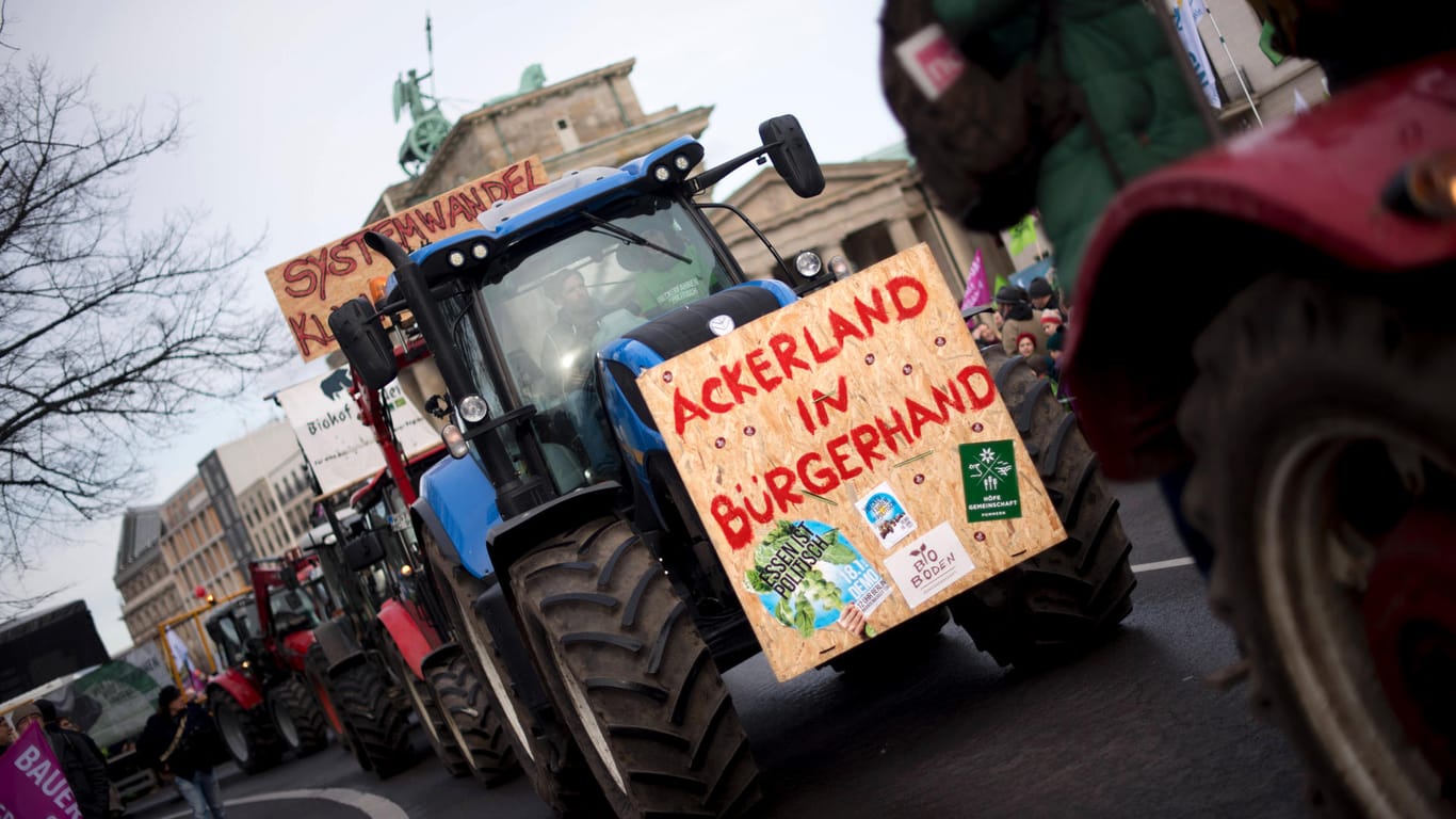 Traktor mit Transparent "Ackerland in Bürgerhand" vor dem Brandenburger Tor: Das Foto stammt von einer Demo im Januar – nun demonstrieren die Landwirte erneut.