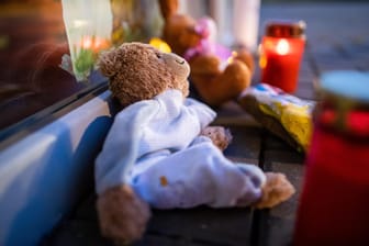 Zwei Stofftiere und Kerzen liegen vor dem Eingang einer Kindertagesstätte: Vor dem Vorfall gab es keine Beschwerden gegen die Erzieherin.