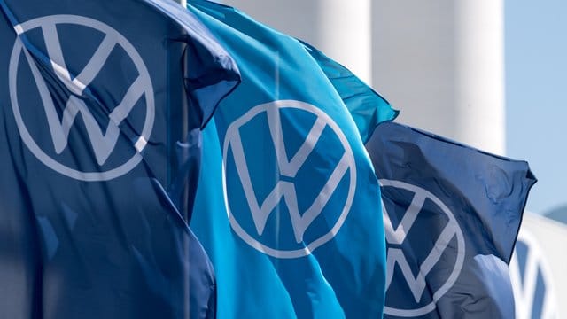 Fahnen mit dem VW-Logo wehen vor einem Fahrzeugwerk