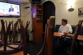 Ein Restaurantbesitzer schaut sich in Paris auf einem Nachrichtensender eine Fernsehansprache des französischen Premierministers Philippe an.