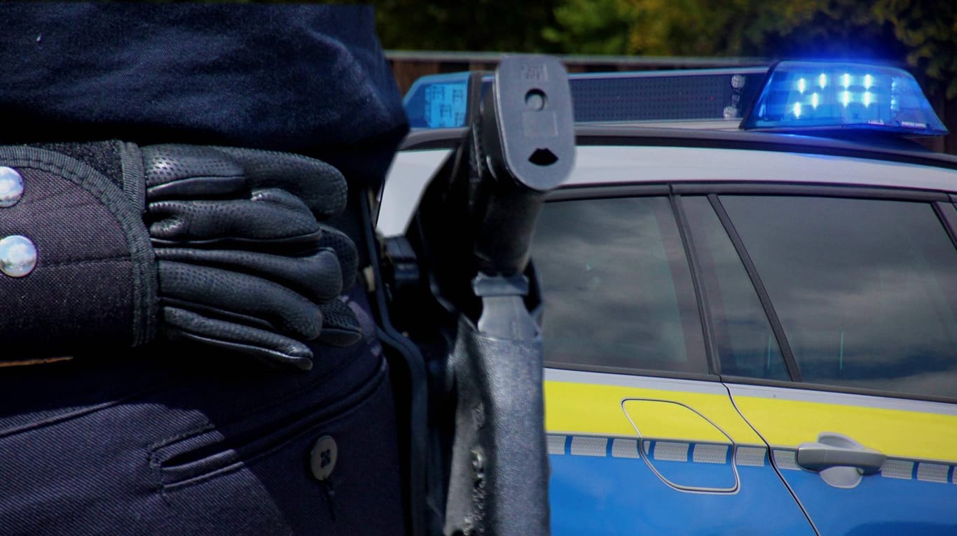 Ein Polizist mit einem Streifenwagen im Hintergrund (Symbolbild): In Hagen hat es offenbar einen Raubüberfall auf ein Haus gegeben.