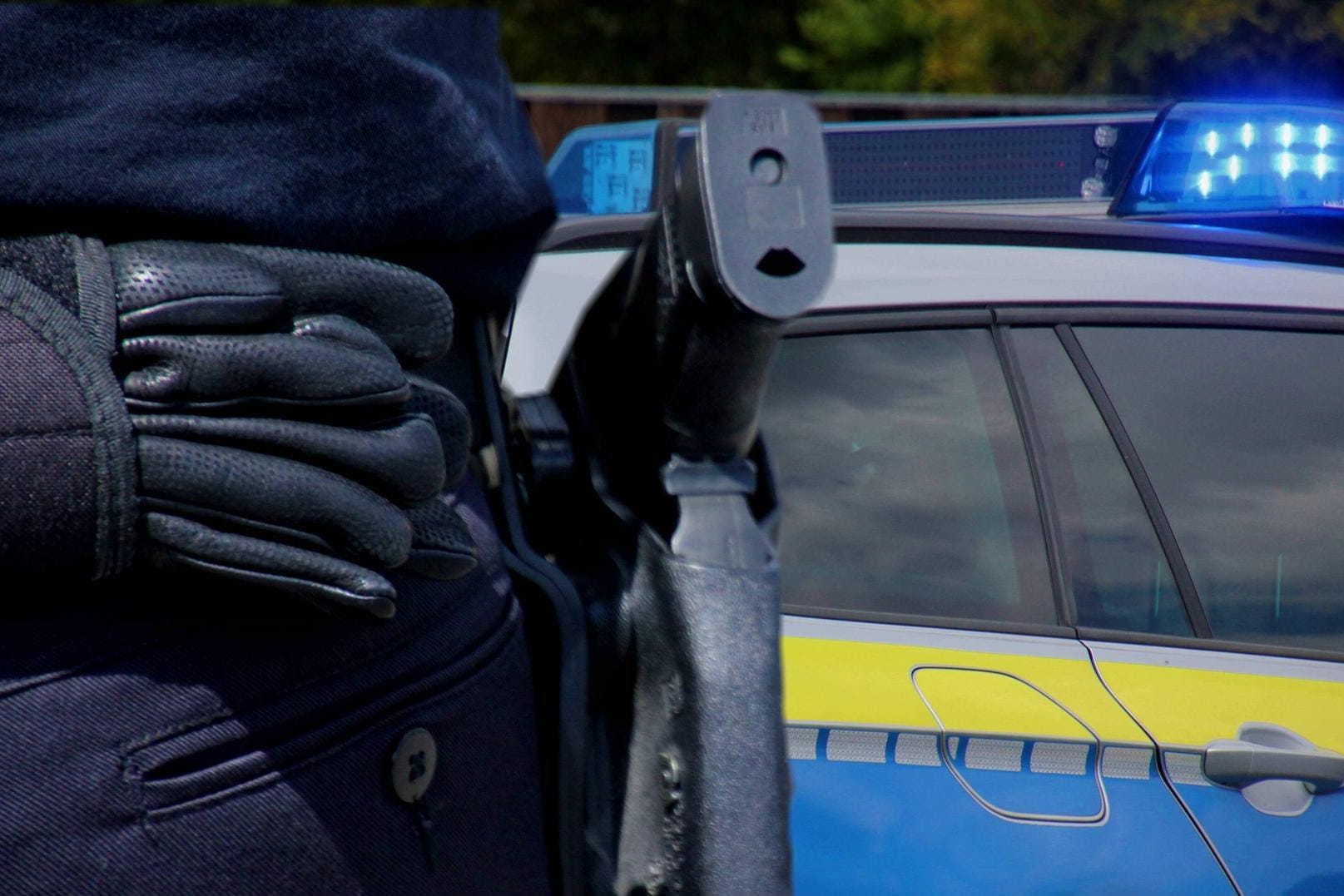 Ein Polizist mit einem Streifenwagen im Hintergrund (Symbolbild): In Hagen hat es offenbar einen Raubüberfall auf ein Haus gegeben.