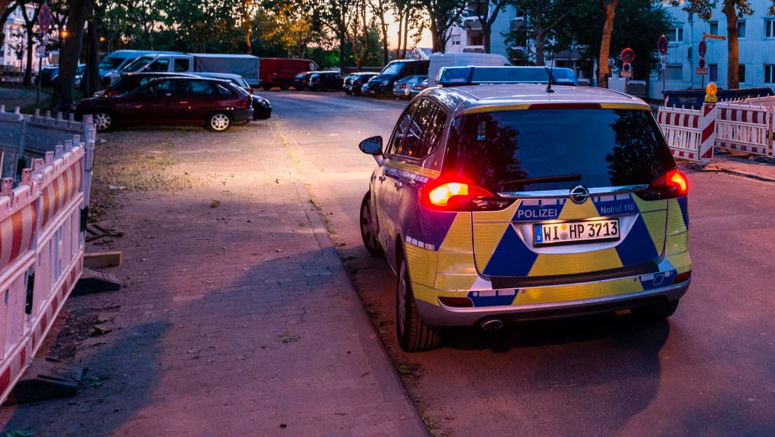 Ruhe nach dem Sturm in Dietzenbach: Ein Polizeifahrzeug steht am Rande der Hochhaussiedlung, in der die Polizei in einen Hinterhalt gelockt wurde.