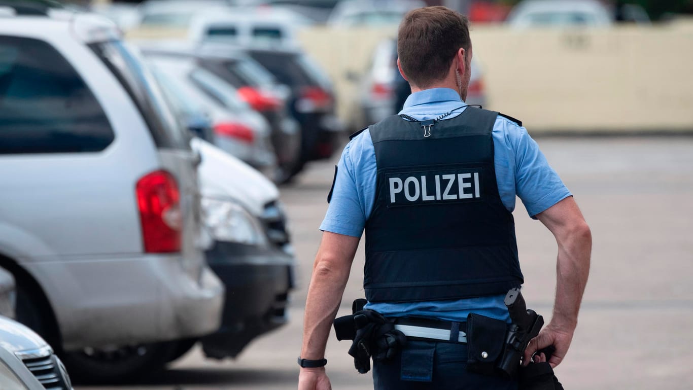 Ein Polizist geht über den Parkplatz einer Hochhaussiedlung in Dietzenbach: Nachdem am Freitag Einsatzkräfte von einer Gruppe Männer mit Steinen attackiert worden waren, gehen die Ermittlungen der Behörden nun weiter.