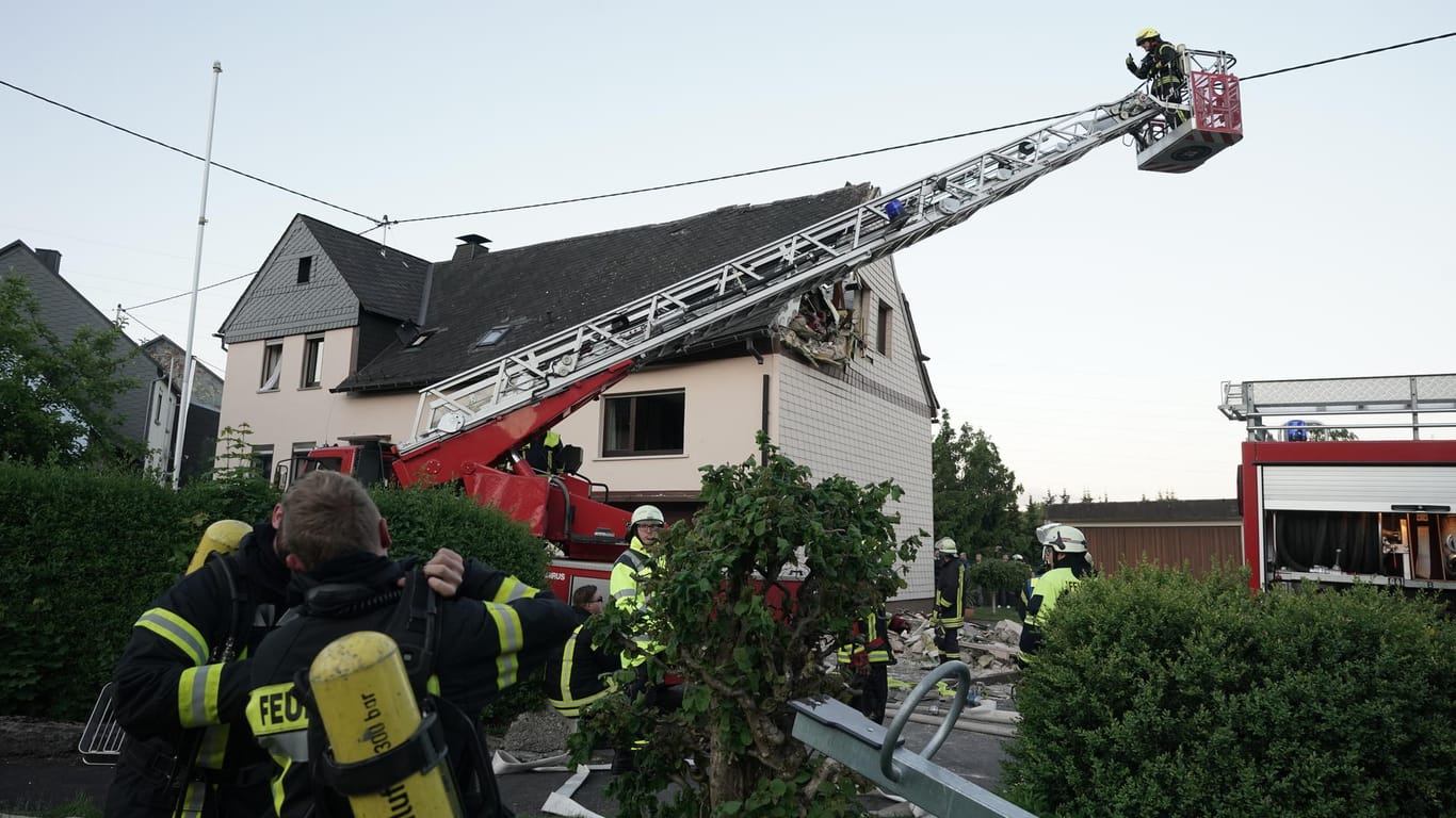 Feuerwehrleute sichern ein Wohnhaus, nachdem ein Kleinflugzeug am Samstag in das Dach gestürzt ist.