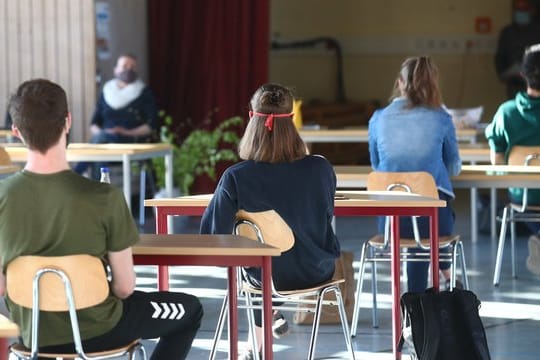 Schüler mit Mundschutz sitzen an ihren Tischen (Symbolbild): In Thüringen kehren nun alle Kinder und Jugendliche wieder zurück.