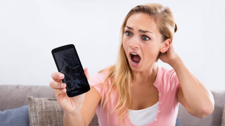 Frau starrt erschrocken auf ihr Handy: Ein Bild kann derzeit Android-Smartphones unbenutzbar machen