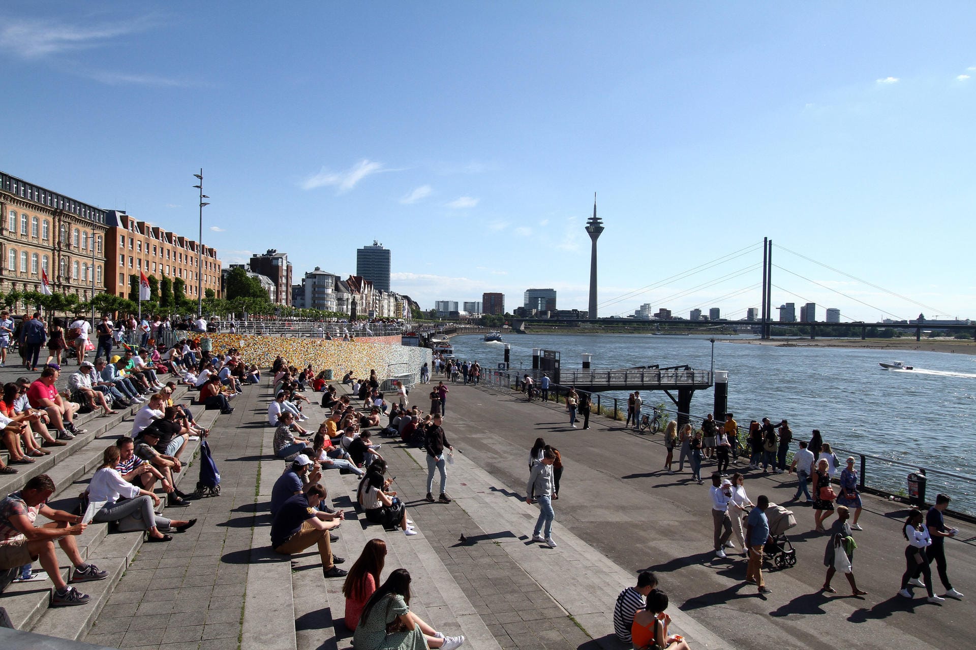 Menschen in Düsseldorf genießen die Sonne am Rheinufer: Zu Beginn der Woche wird es nochmal richtig warm – danach ist es mit dem Sonnenbaden wohl erstmal vorbei.