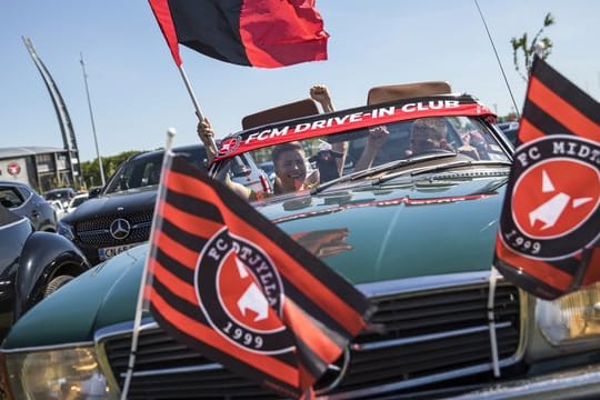 Fußballfans verfolgen das Spiel zwischen dem FC Midtjylland und dem AC Horsens auf dem Parkplatz vor dem Stadion.