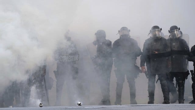 Polizisten während eines Protests in Atlanta inmitten einer Tränengaswolke. Polizisten während eines Protests in Atlanta inmitten einer Tränengaswolke.
