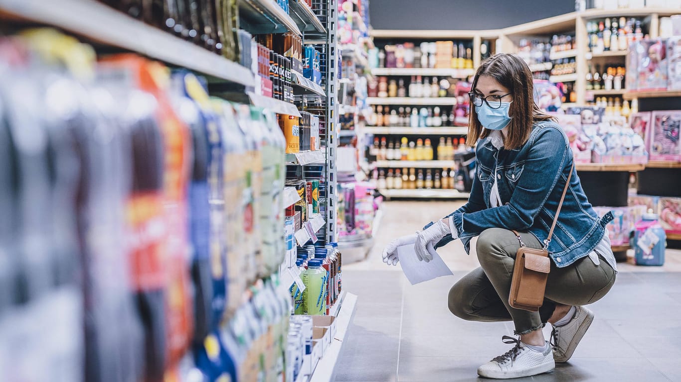 Eine Frau hockt vor Getränken in einem Supermarkt (Symbolbild): In München sind mehrere vergiftete Getränkeflaschen aufgetaucht.