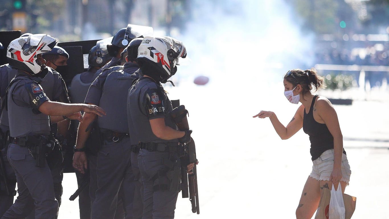 Eine Demonstratin in Brasilien steht der Polizei gegenüber. Sie demonstriert gegen die Corona-Politik des Präsidenten Jair Bolsonaro. Obwohl die Fallzahlen steigen, nimmt er die Gefahr nicht ernst.