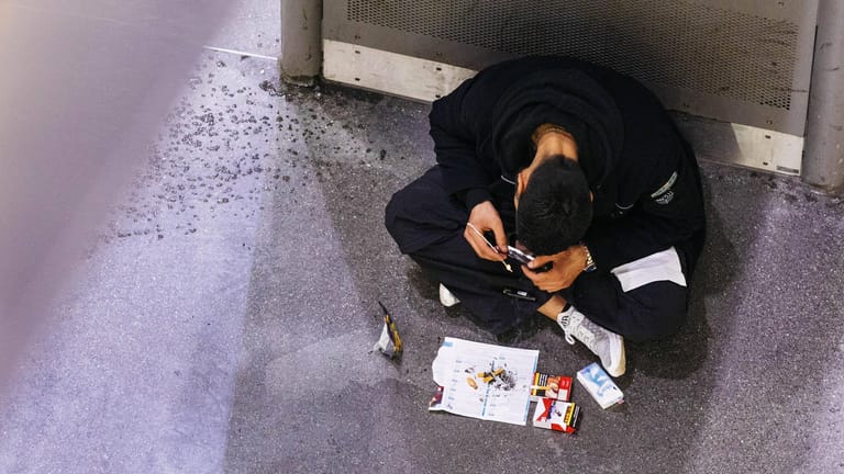 Ein Junkie raucht Heroin von einer Folie in einer U Bahn Haltestelle in Köln: Ein mobiles Drogenhilfeangebote wird gut angenommen.