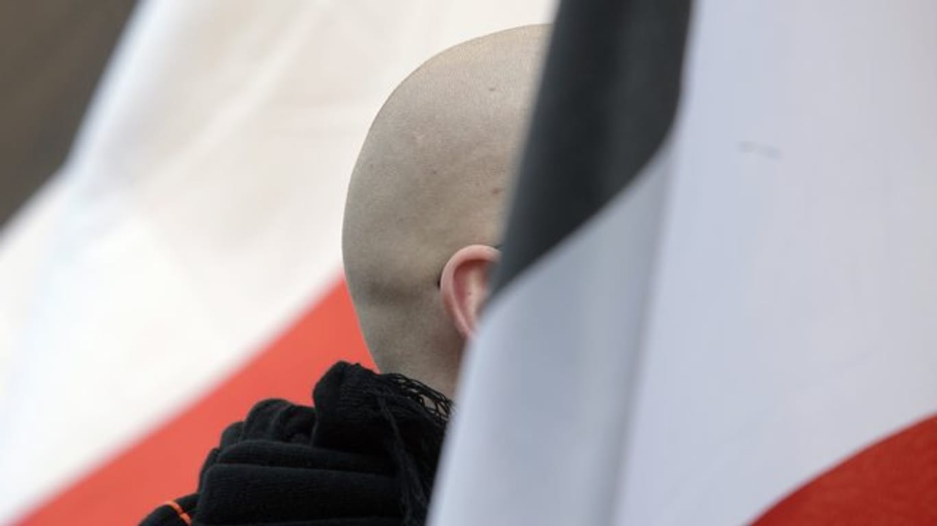 En Mann mit geschorenem Kopf zwischen schwarz-weiß-roten Fahnen: Momentaufnahme einer Demo.