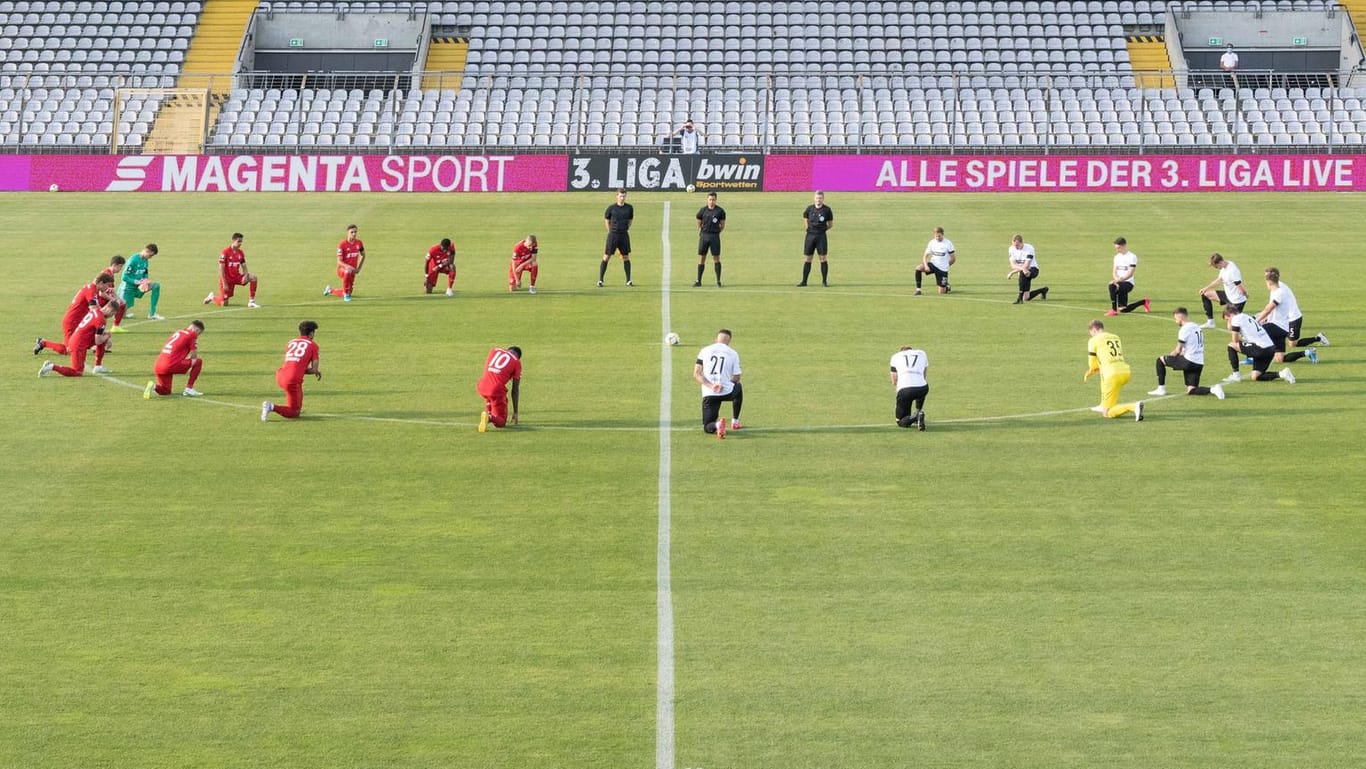 Vor dem Anpfiff: Die Spieler von Bayern II und Preußen Münster knien am Mittelkreis.