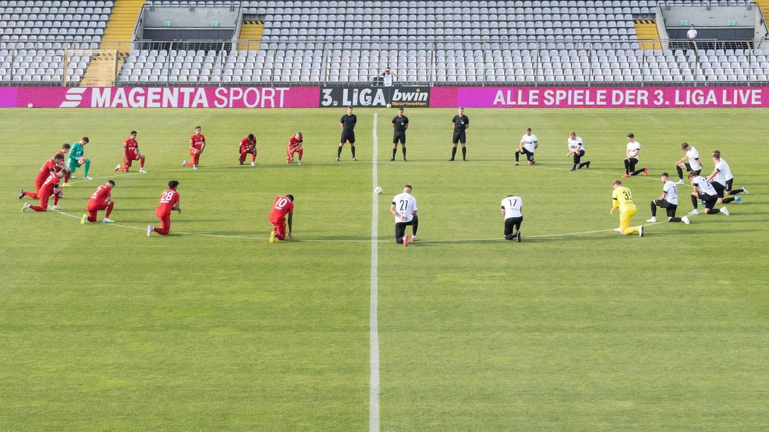 Vor dem Anpfiff: Die Spieler von Bayern II und Preußen Münster knien am Mittelkreis.