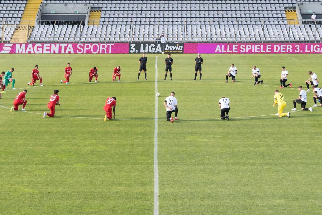 Vor dem Anpfiff: Die Spieler von Bayern II und Preußen Münster knien am Mittelkreis.