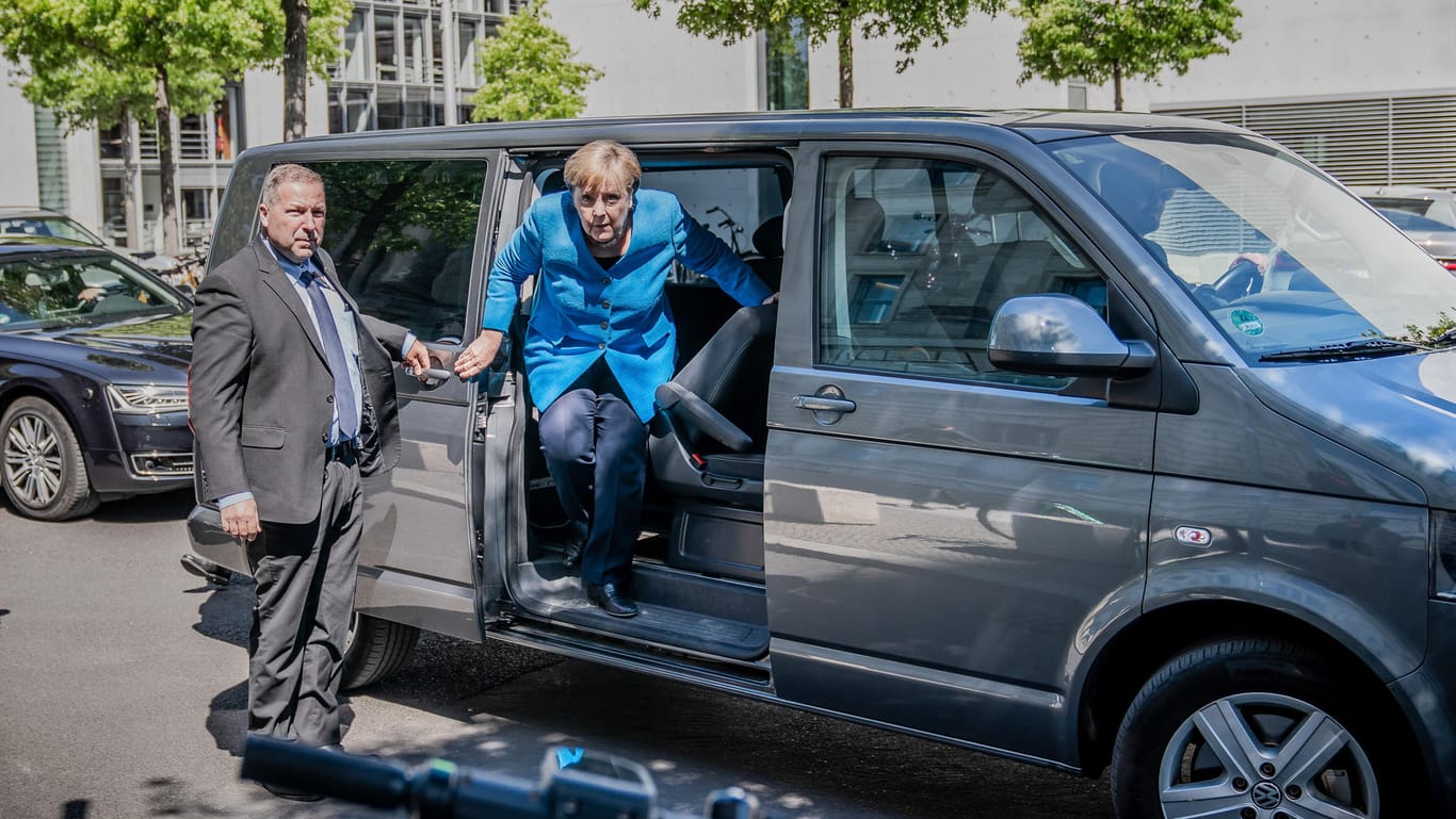 Angela Merkel steigt neben einem Bodyguard vor dem Bundestag aus einem Bus. Während der Corona-Krise lässt sich die Kanzlerin häufig in dem Minibus chauffieren, um die Abstandsregeln einzuhalten.