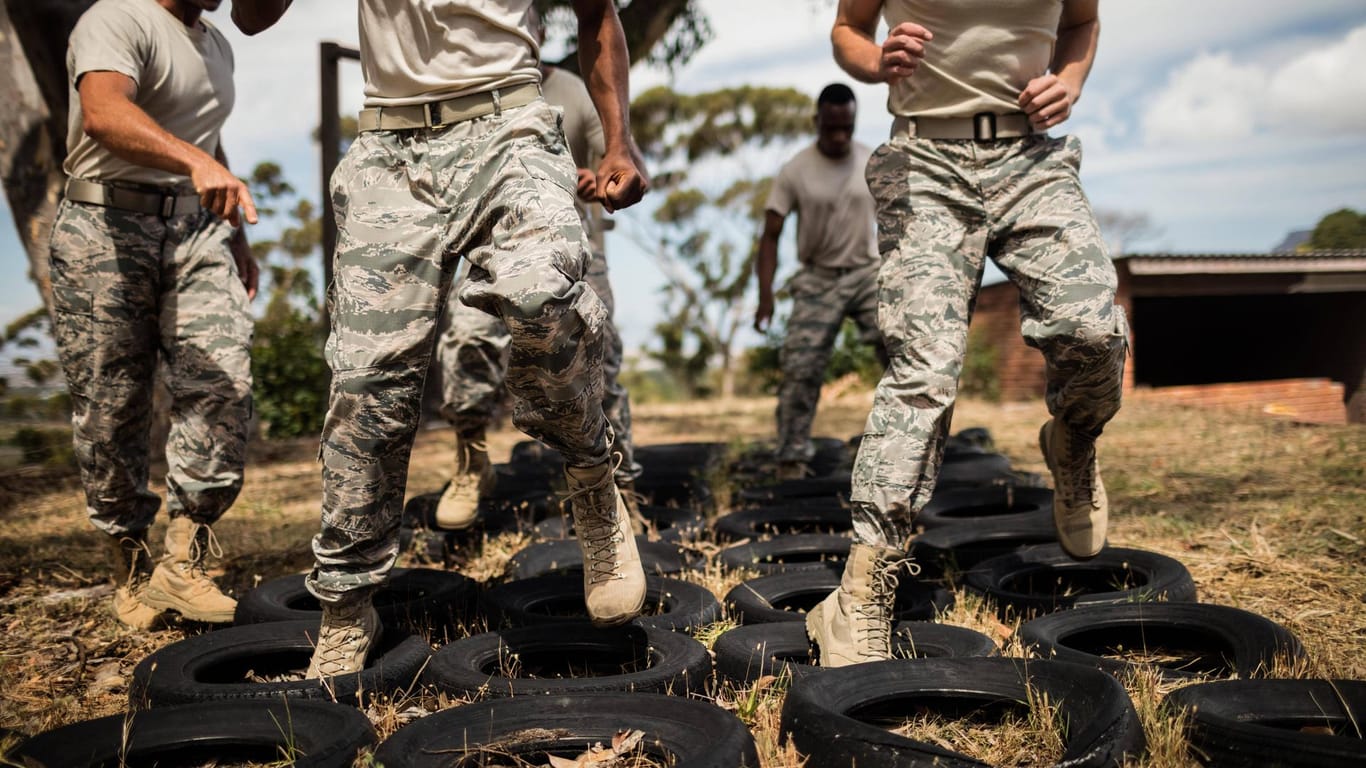 Junge Männer springen in einem Militärtraining über Reifen. (Symbolfoto)