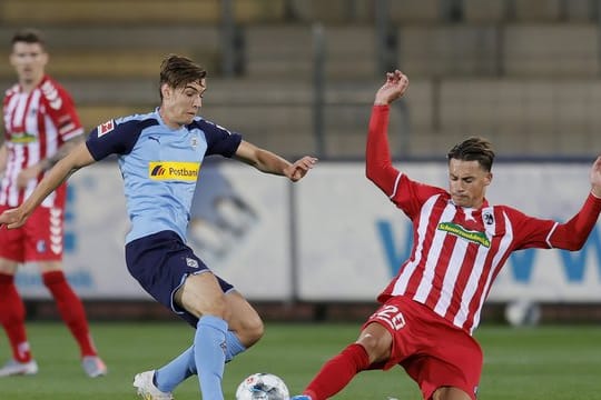 Der Freiburger Robin Koch (r) grätscht gegen Florian Neuhaus.