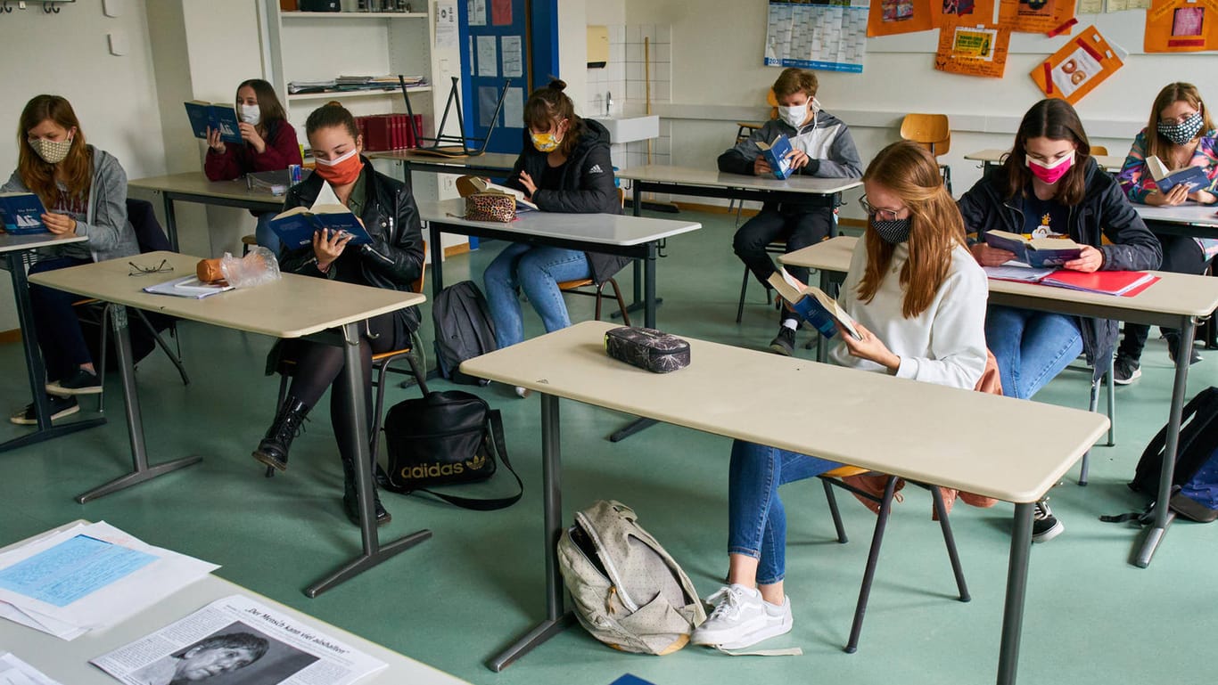 Mit Abstand und Mundschutz sitzen Schüler in einem Klassenraum: Der Deutsche Lehrerverband kann sich den Normalbetrieb in Schulen unter Umständen vorstellen.