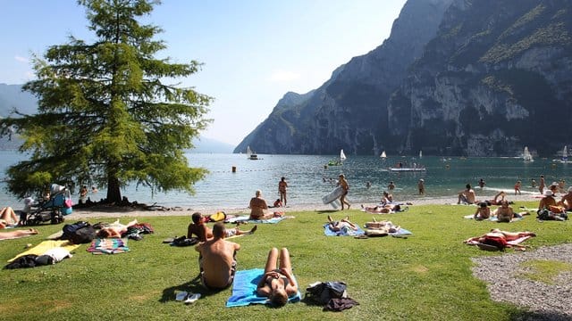 Touristen und Einheimische nehmen am Strand von Riva del Garda ein Sonnenbad. Touristen und Einheimische nehmen am Strand von Riva del Garda ein Sonnenbad.