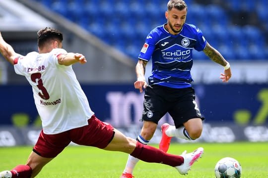 Der Nürnberger Konstantinos Mavropanos (l) grätscht in den Lauf von Arminia-Spieler Jonathan Clauss.