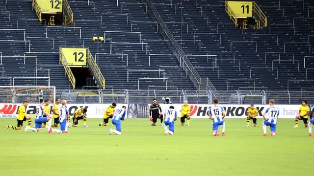 Spieler beider Mannschaften knien vor dem Anpfiff um den Mittelkreis und schweigen ein paar Minuten. Spieler beider Mannschaften knien vor dem Anpfiff um den Mittelkreis und schweigen ein paar Minuten.