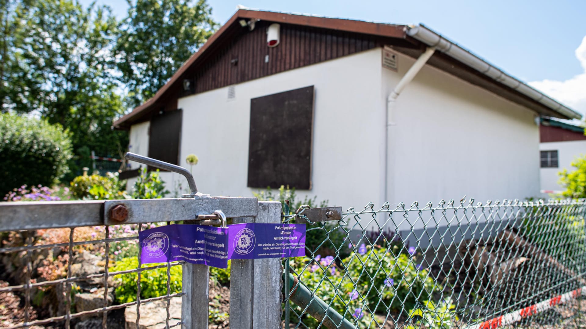 Bei den Ermittlungen nach schwerem sexuellem Missbrauch von Kindern klebt ein Polizeisiegel an dem Gartentor vor der Gartenlaube, wo der vermutliche Haupttäter Teile seiner Server-Anlage unterbrachte.