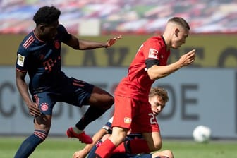 Leverkusens Florian Wirtz (r) setzt sich gegen Alphonso Davies vom FC Bayern durch.