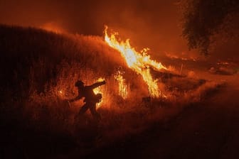 Ein Feuerwehrmann entzündet kontrollierte Gegenfeuer, um die Ausbreitung des Waldbrands zu verhindern.
