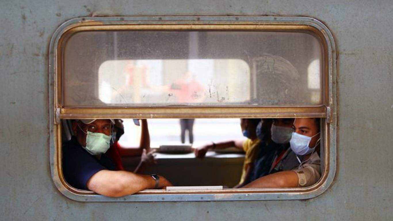 Menschen mit Gesichtsmasken sitzen in einem Zug in Kairo.