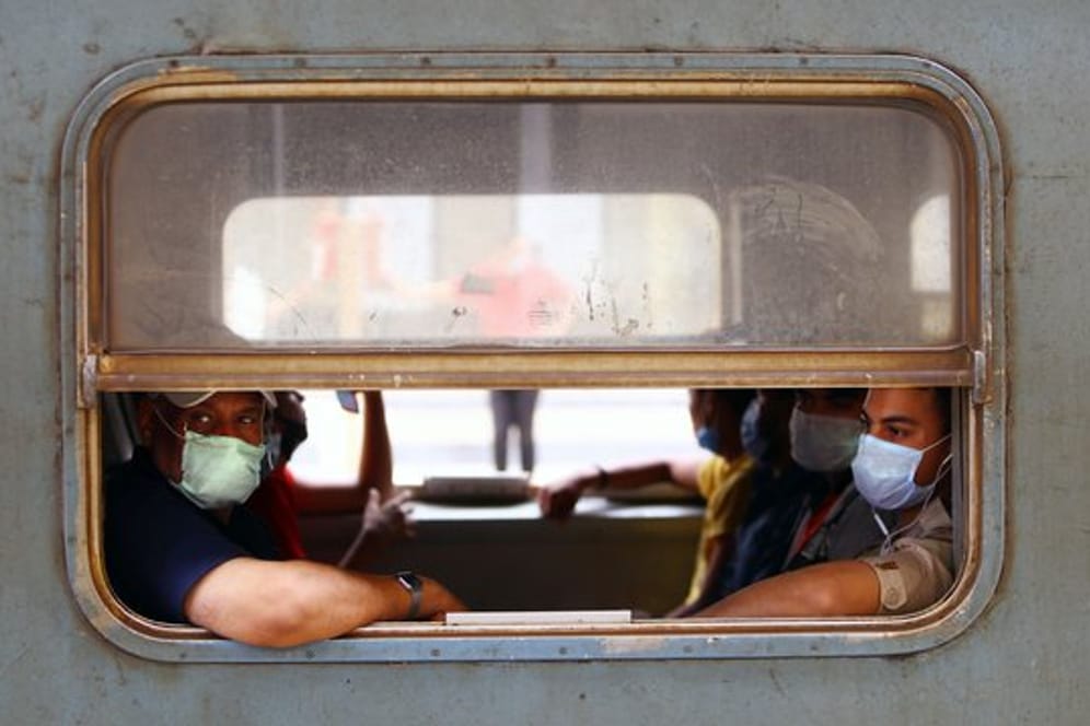 Menschen mit Gesichtsmasken sitzen in einem Zug in Kairo.