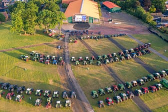 Aufnahme von Treckern aus der Luft: Landwirte sitzen am Abend in ihren Fahrzeugen auf einer großen Wiese und schauen sich den Dokumentarfilm "Die schöne Krista" über eine Kuh aus Niedersachsen an.