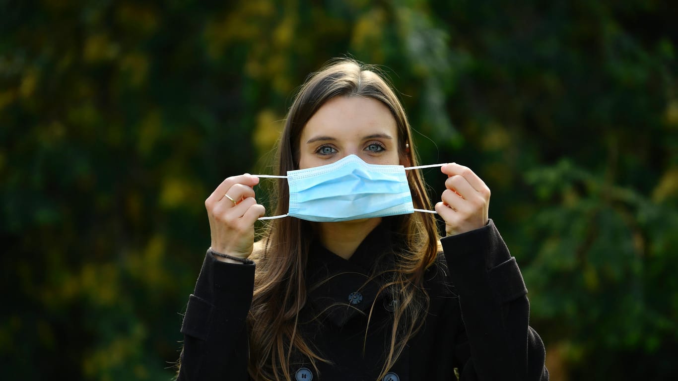 Eine Frau hält eine Mundschutzmaske vor dem Gesicht (Symbolbild): Forscher bestätigen, dass Masken die Verbreitung des Coronavirus verlangsamt haben.