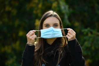 Eine Frau hält eine Mundschutzmaske vor dem Gesicht (Symbolbild): Forscher bestätigen, dass Masken die Verbreitung des Coronavirus verlangsamt haben.