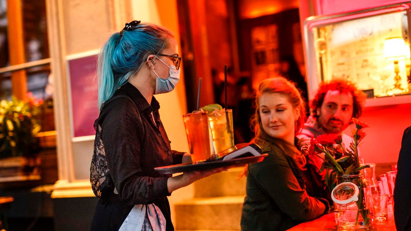 Eine Kellnerin serviert Cocktails an einem Tisch vor der Cocktailbar "Limonadier": In Berlin sollen Lokale länger als nur bis 23 Uhr öffnen dürfen.