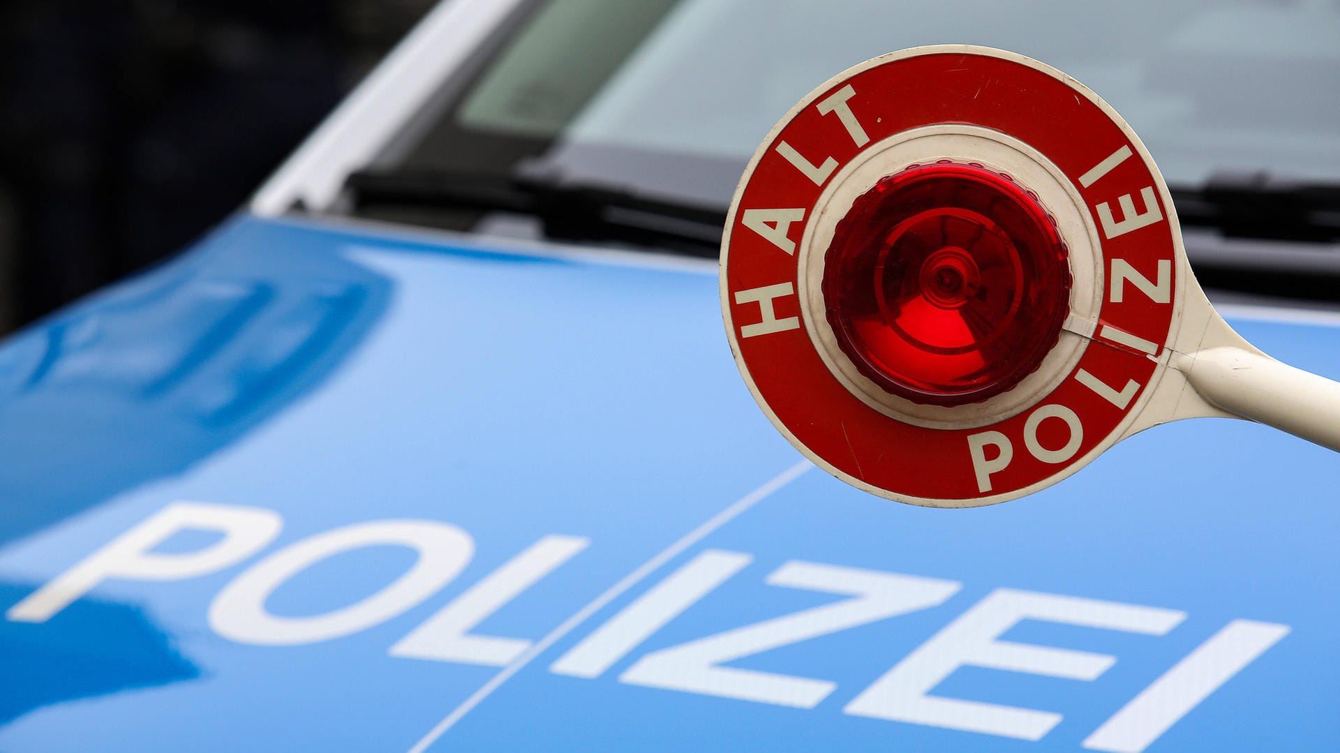 Eine Polizeikelle ist vor einem Streifenwagen zu sehen (Symbolbild): Beamte in Essen haben zwei Nackte in einem gestohlenen Fahrschulauto gestoppt.