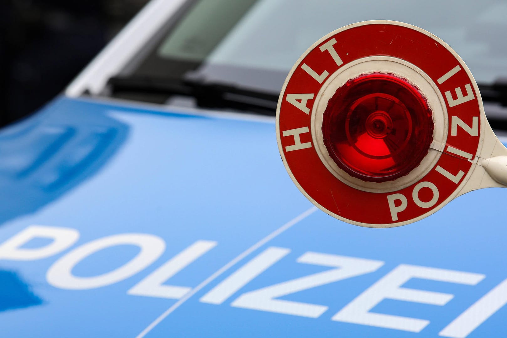 Eine Polizeikelle ist vor einem Streifenwagen zu sehen (Symbolbild): Beamte in Essen haben zwei Nackte in einem gestohlenen Fahrschulauto gestoppt.