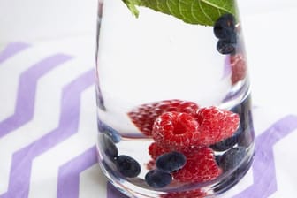 Bei Hitze ist mit Beeren und Minze versetztes Wasser besonders erfrischend: Aus Hygienegründen sollten Obst und Kräuter aber regelmäßig ausgewechselt werden.