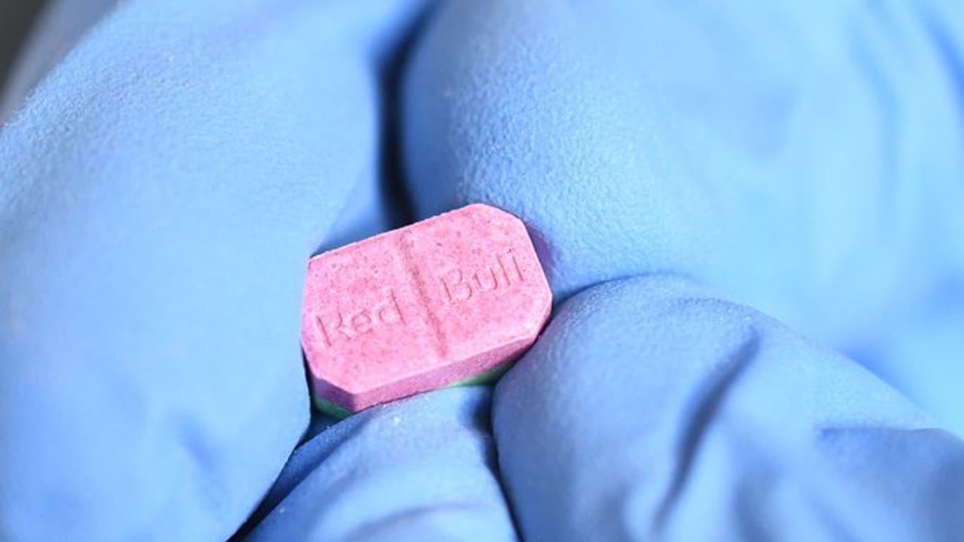 Ein Zollmitarbeiter zeigt eine Ecstasy-Pille.