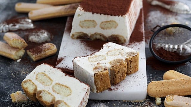 Schichtweise kommen Eis und Löffelbiskuits in eine Kastenform.