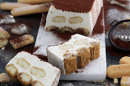 Schichtweise kommen Eis und Löffelbiskuits in eine Kastenform.