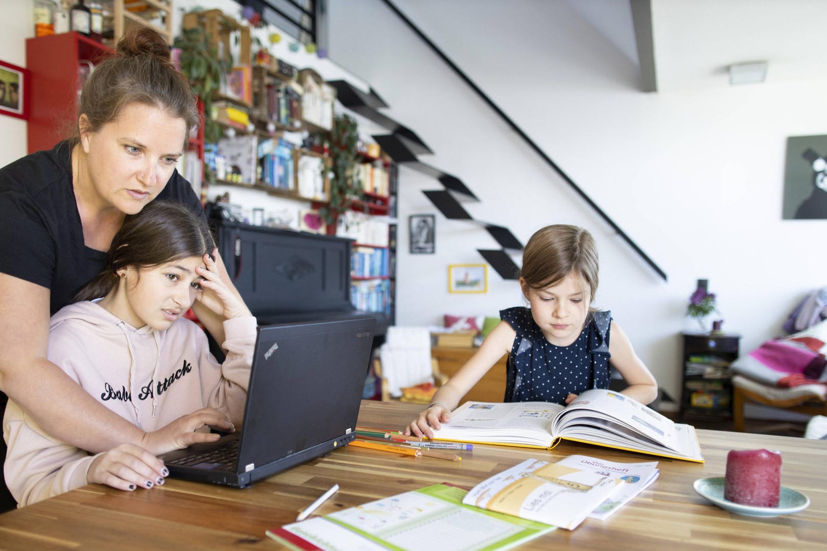 Eine Frau mit zwei Mädchen beim Homeschooling (Symbolbild): Nach monatelangem Ausnahmezustand soll der Regelbetrieb an Schulen und Kitas in Hessen wieder beginnen.