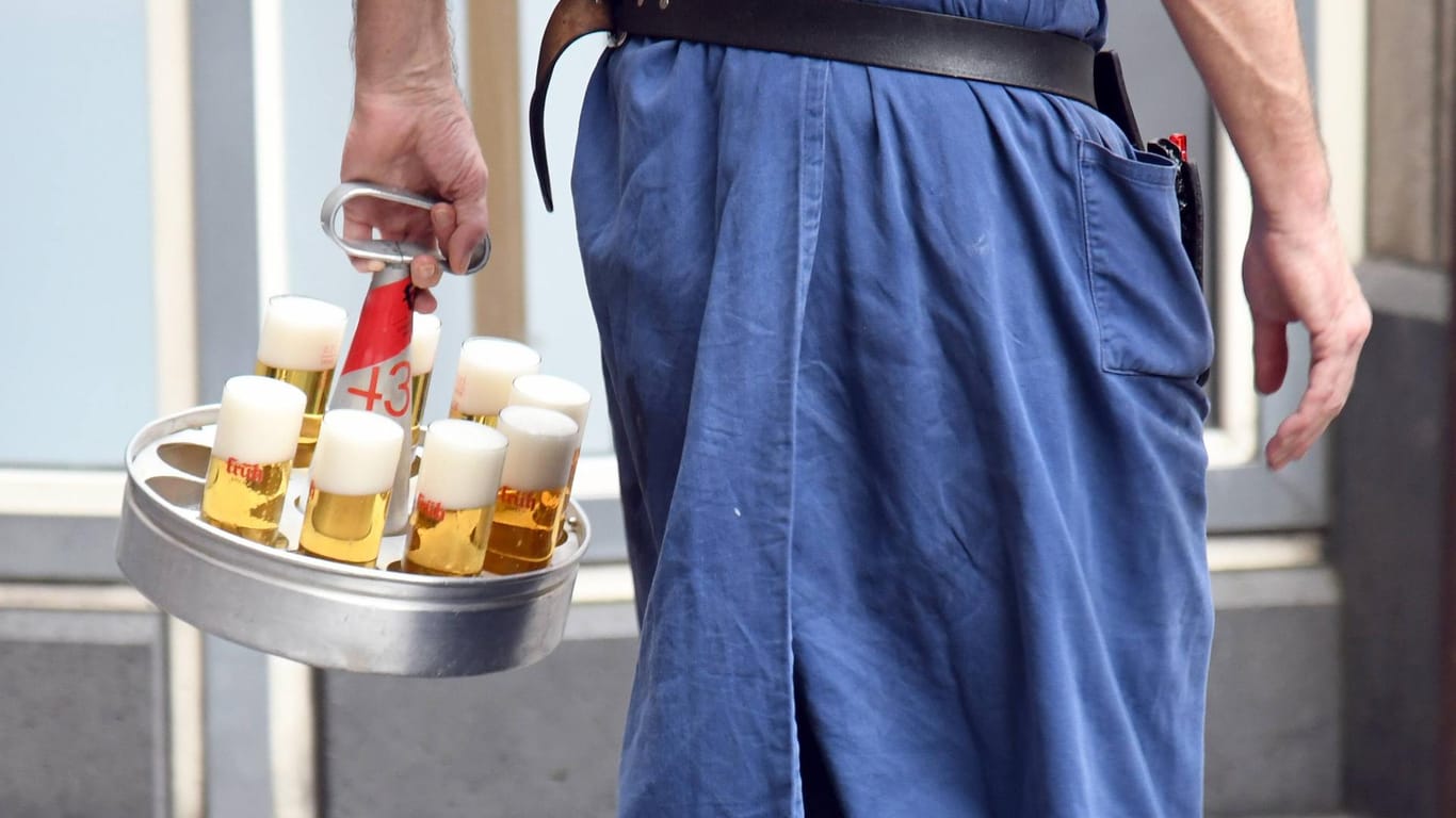 Ein Kölner Kellner serviert in einem Kölner Brauhaus Kölsch: Drei Kölsch-Brauereien wehren sich gegen Geldbußen.