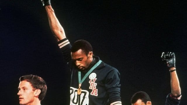 Die US-Athleten Tommie Smith (M) und John Carlos (r) streckten während Olympia 1968 die Fäuste, um gegen Rassismus zu protestieren. Die US-Athleten Tommie Smith (M) und John Carlos (r) streckten während Olympia 1968 die Fäuste, um gegen Rassismus zu protestieren.